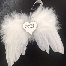 Load image into Gallery viewer, white feathers are used to make angel wings with a white organaza ribbon to hang, in the centre is a white heart with personalised name hand written
