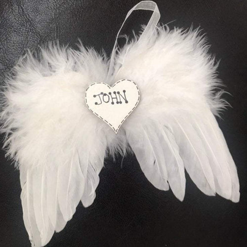 white feathers are used to make angel wings with a white organaza ribbon to hang, in the centre is a white heart with personalised name hand written