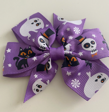 Load image into Gallery viewer, girls halloween hair clip bow. a pattern of ghosts, cats and skeletons on a purple bow
