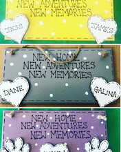 Load image into Gallery viewer, hand painted in grey this rectanglular wall plaque is 6&quot; x 3&quot;. with New home, New adventures, New memories hand written. Family Members names are written in 4cm white hearts and family pets are written on 4cm white paws. white spots pattern can be added to the grey. Hung with jute string twine
