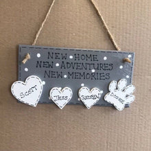 Load image into Gallery viewer, hand painted in grey this rectanglular wall plaque is 6&quot; x 3&quot;. with New home, New adventures, New memories hand written. Family Members names are written in 4cm white hearts and family pets are written on 4cm white paws. white spots pattern can be added to the grey. Hung with jute string twine
