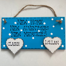 Load image into Gallery viewer, hand painted in blue this rectanglular wall plaque is 6&quot; x 3&quot;. with New home, New adventures, New memories hand written. Family Members names are written in 4cm white hearts and family pets are written on 4cm white paws. white spots pattern can be added to the blue. Hung with jute string twine
