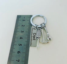 Load image into Gallery viewer, metal keyring with metal charms which include hammer,wrench,screwdriver and a ruler which is engraved with the word dad , next to a ruler for size which is roughly 5cm
